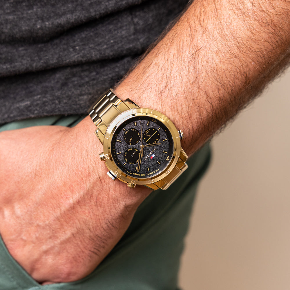 Tommy Hilfiger Troy chronograph watch worn on wrist with black dial and gold case